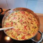 Cabanossi-Käse-Suppe in einer Schüssel, dekoriert mit frischen Kräutern.