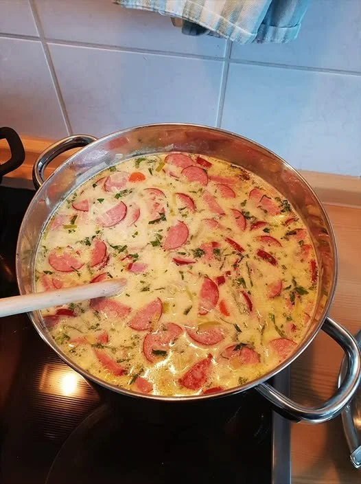 Cabanossi-Käse-Suppe in einer Schüssel, dekoriert mit frischen Kräutern.