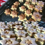 Linzer Sterne Plätzchen mit Marmelade und Puderzucker dekoriert.