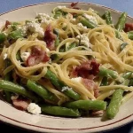 Bandnudeln mit grünen Bohnen, Bacon und Schafskäse auf einem Teller serviert.