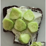 Brot mit Frischkäse und Gurke auf einem Teller serviert