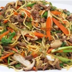 Chinesisch gebratene Nudeln mit Hühnchen, Ei und Gemüse auf einem Teller