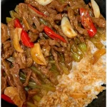 Chinesisches Rindfleisch mit Zwiebeln und Paprika auf einem Teller serviert.