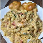 Cremige Pasta mit Hähnchen, Spinat und Tomaten auf einem Teller serviert