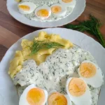 Eier in Dillsoße mit Kartoffeln auf einem Teller serviert