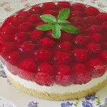 Frische Himbeertorte mit Schmand auf einem Teller, dekoriert mit Himbeeren.