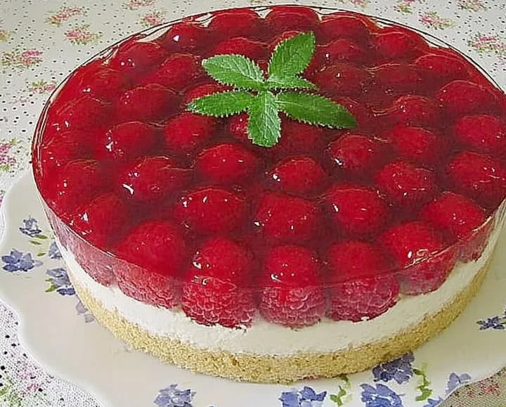 Frische Himbeertorte mit Schmand auf einem Teller, dekoriert mit Himbeeren.