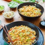 Teller mit gebratenen Nudeln, Ei und buntem Gemüse