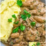 Geschnetzeltes mit Champignon-Rahmsoße und Kartoffelpüree auf einem Teller serviert