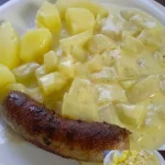 Kohlrabi Bratwurst mit Kartoffeln auf einem Teller serviert