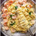 Ein Teller Nudeln mit Krabben in würziger Sauce und frischen Kräutern.