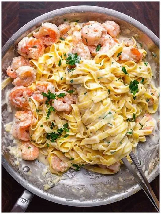 Ein Teller Nudeln mit Krabben in würziger Sauce und frischen Kräutern.