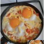 Spiegeleier mit Paprika und Käse auf einem Teller serviert.