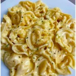 Tortellini mit Sahne in einer Schüssel, garniert mit frischen Kräutern