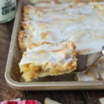 Apfelkuchen-Riegel auf einem Teller mit frischen Äpfeln und Zimt