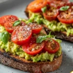 Gesundes Avocadobrot mit frischen Tomaten auf einem Teller angerichtet.