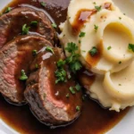 Traditioneller deutscher Sauerbraten mit Beilagen auf einem Teller serviert.