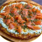 Köstliche Kartoffelpizza mit frisch mariniertem Lachs auf einem Holzbrett serviert.