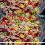 Schinken Salat mit Käse und Paprika auf einem weißen Teller serviert